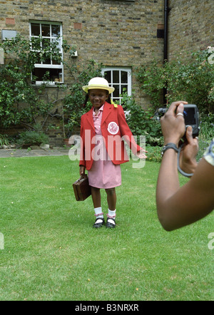 Black mother takes a photo of her daughter's first day at school Stock Photo