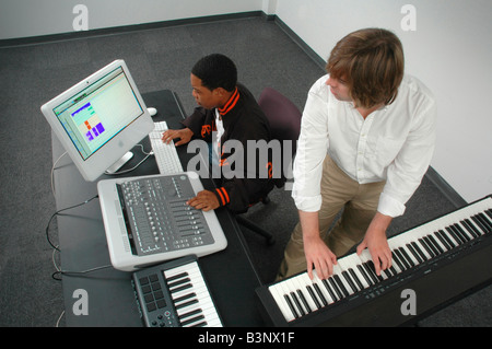 Two men in an audio production session one at keyboard the other at the mixing board Stock Photo