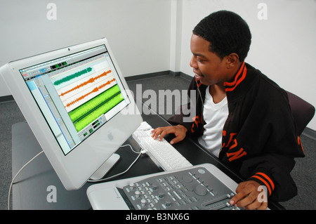 African American Black young man composing arranging and recording music on a computer Stock Photo