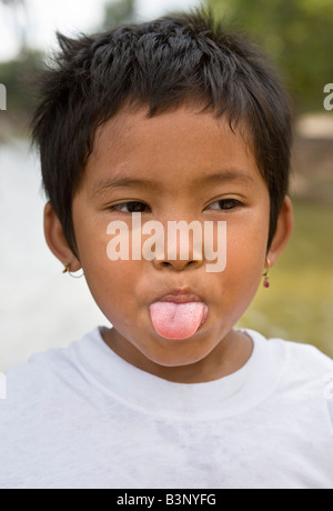 Young Child selling postcards pokes her tongue out Angkor Cambodia Stock Photo