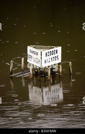 A sign in a quarry in County Durham, England, warns of deep water and hidden hazards. Stock Photo