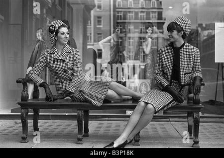 Fashions taken during London Fashion Week 1964 Models wearing two piece suits with matching hats sitting on a bench talking Stock Photo