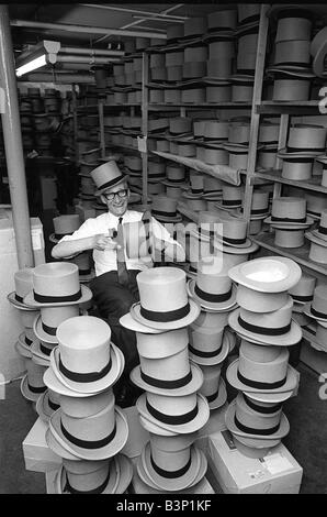 Man happily brushing top hats at a suit hire company in preparation for Royal Ascot June 1968 1960s Stock Photo