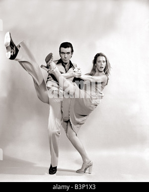 Dancing Duo John and June demonstrate the dance The Tango Hustle which has taken New York By Storm in the Film Saturday Night Fever Wearing 1970s fashion flared trousers waistcoat black shirt greased back hair Julie is wearing Dress and silver stilettos Modern Latino type dancing Disco dancing with the Medallion man March 1978 Stock Photo