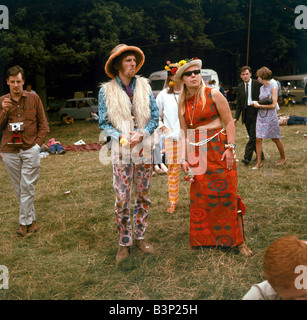 Sixties Fashion 1960s clothing Hippies at flower festival Fur waistcoat Hat sunglasses Floral trousers and dress Mirrorpix Stock Photo