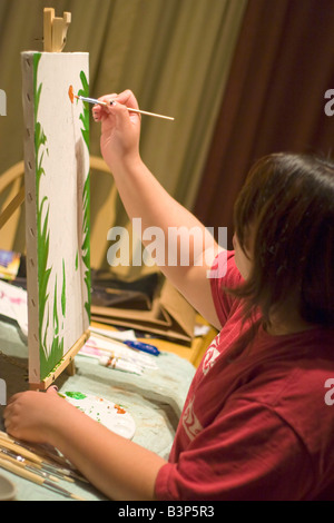 A young woman doing working with oil paints on canvas Stock Photo