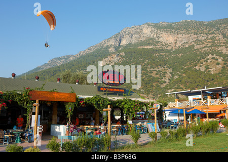 Tandem paragliders fly above popular Help Bar in the resort village of Oludeniz Province of Mugla Turkey Stock Photo