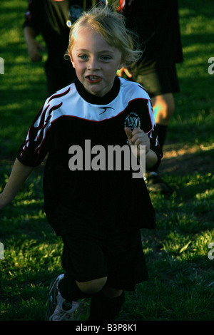 Cute blond child running in from soccer game Stock Photo