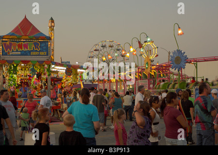 Fairgoers strolling among rides and attractions on a state fair midway. Stock Photo