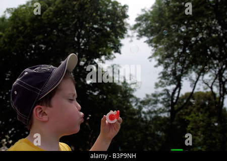 seven-year-old boy blowing bubbles Stock Photo