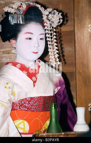 Japan, Kyoto. Maiko trainee geisha entertaining at dinner and serving drinks Stock Photo