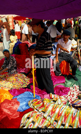 China, Xinjiang Uigur Autonomous Region, Kashgar. Bolts of vibrant cloth add colour to Kashgar's Sunday Market Stock Photo