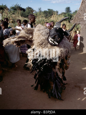 Malawi, Mua, Central Malawi. The Chewa people, Malawi's largest ethnic group, live on the west side of Lake Malawi. Despite years of missionary influence, they still cling to old beliefs and rituals. For them, death simply means a journey of rebirth into the spirit world. The terrestrial representatives of this other world are grotesquely masked dancers known as Gule Wamkulu. When a person dies, masked dancers appear at the funeral to welcome the deceased to the spirit world. Stock Photo