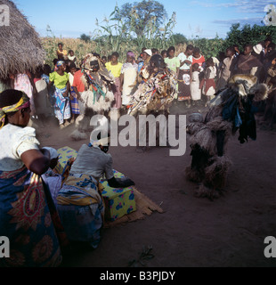 Malawi, Mua, Central Malawi. The Chewa people, Malawi's largest ethnic group, live on the west side of Lake Malawi. Despite years of missionary influence, they still cling to old beliefs and rituals. For them, death simply means a journey of rebirth into the spirit world. The terrestrial representatives of this other world are grotesquely masked dancers known as Gule Wamkulu. When a person dies, masked dancers appear at the funeral to welcome the deceased to the spirit world. Stock Photo