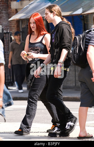 Camden Market Stables , pretty female goth teenage girl with red hair walks with male boy with ponytail dressed in jeans by road Stock Photo