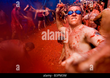 Man wearing swimming goggles throwing a tomato at La tomatina food fighting festival. Bunol. Valencia Spain Stock Photo