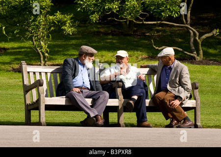 Regent's Park Gardens , scene of three very old men sitting on bench having animated discussion and enjoying the summer sun Stock Photo