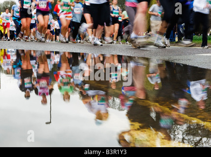 marathon runners reflected in puddle Stock Photo