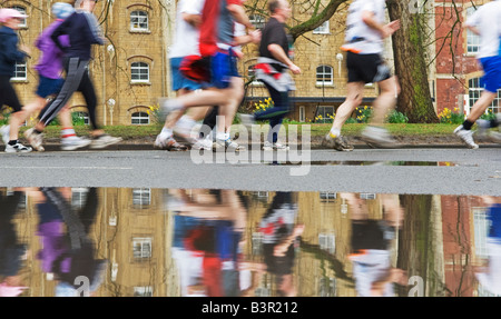 marathon runners reflected in puddle Stock Photo