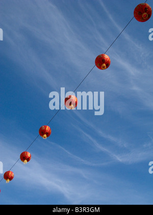 Red chinese new year lanterns against blue sky and swirling clouds. Stock Photo