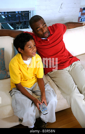 African American father and son watching TV on a couch Stock Photo