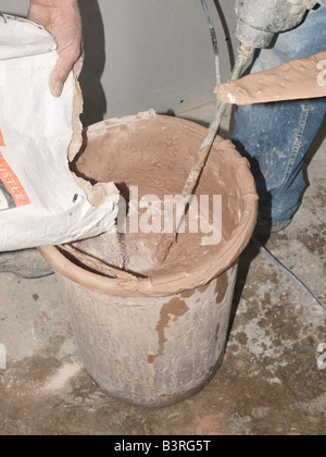 PLASTER MIXING PADDLE AND CONTAINER OF MIXED PLASTER ON SITE WITH BARE ...
