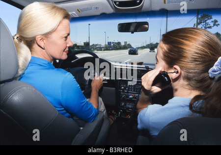 Mother and teenage daughter in car together, daughter on phone