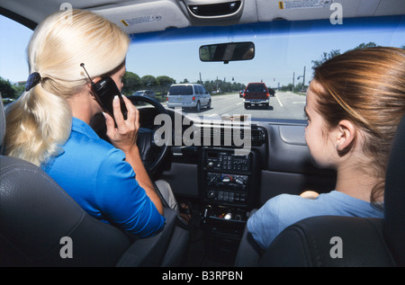 Mother and teenage daughter in car together, daughter on phone