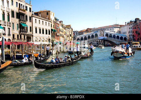 Gondolas and barges near the Rialto Bridge on the busy Grand Canal in Venice Stock Photo