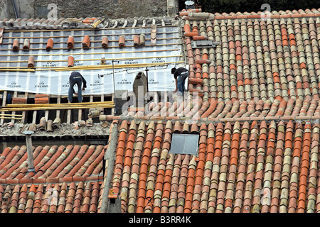 Workers In Carcassone, Fance Work On Patching A Red Tile Roof Stock 