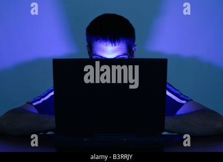 Man Using a Laptop with His Face Illuminated by the Screen Stock Photo