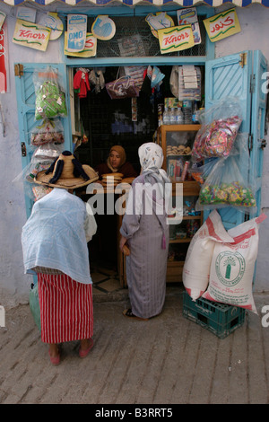 Women buying bread and supplies from one of the many small shops in the narrow pedestrian streets of old Chefchaouen. Stock Photo