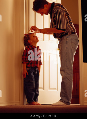 Father measuring son on door frame Stock Photo