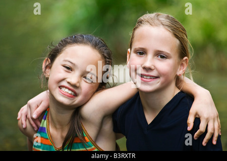 Portrait of two smiling girls hugging in garden Stock Photo - Alamy