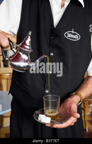Morocco, Tangier. A waiter pours a glass of mint tea, Morocco's favourite drink. Stock Photo