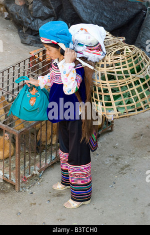 Asia, China, Yunnan Province, Yuanyang. Yi woman carries animal basket at Xinjie market (Old Yuanyang). Stock Photo