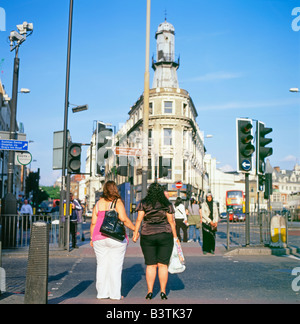 Two women holding hands while crossing York Way at traffic lights near Grays Inn Road, Kings Cross London UK   KATHY DEWITT Stock Photo