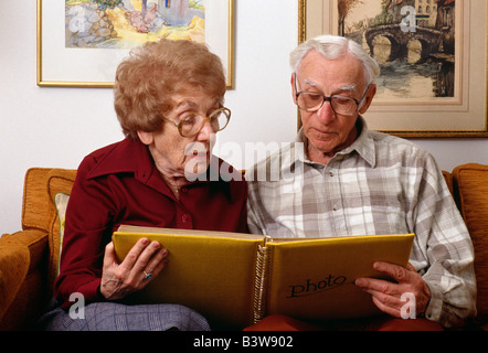Elderly couple looking at a photo album in their home Stock Photo