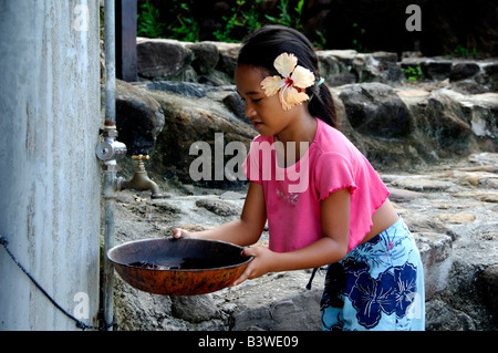 South Pacific, French Polynesia, Moorea, Tiki Village. Young Polynesian girl filling water bowl. Stock Photo