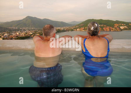 Mexico, Guerrero, Zihuatanejo.  Married senior citizens enjoy the view from their pool above Zihuatanejo Bay.  (MR) Stock Photo