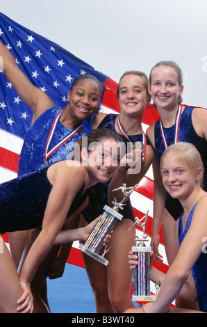 Teenage American gymnasts pose with trophies, medals, and American Flag Stock Photo