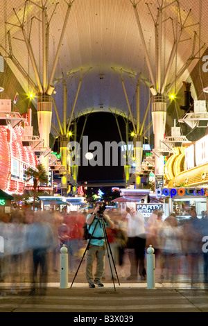 A photographer stands amidst the hustle bustle of Fremont Street in Las Vegas Stock Photo