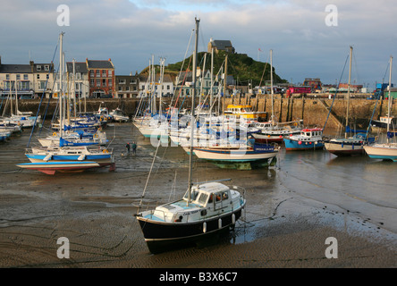 Boats moored at low tide and two fishermen chatting at Ilfracombe harbour, Devon during the late afternoon Stock Photo