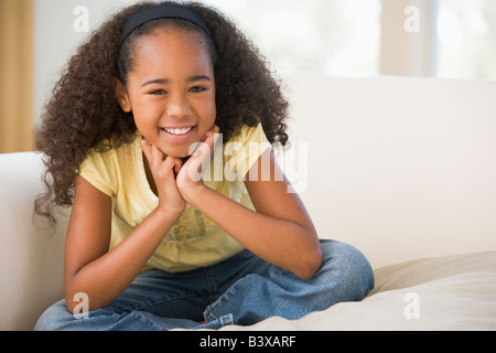 Young Girl Sitting Cross Legged On A Sofa At Home Stock Photo