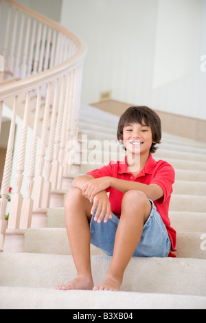 Young Boy Sitting On A Stairwell At Home Stock Photo