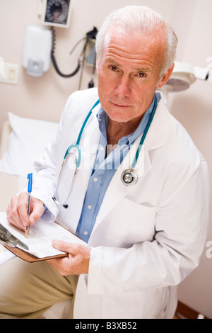Middle Aged Doctor Writing On His Clipboard Stock Photo