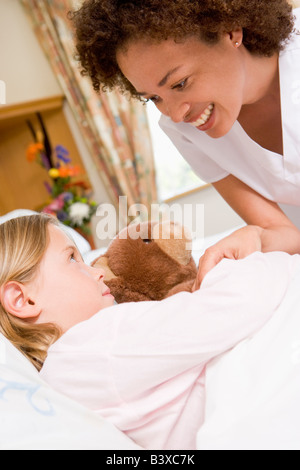 Nurse Checking Up On Young Girl In Hospital Stock Photo