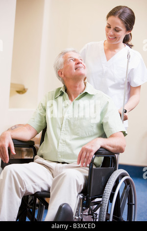 Nurse Pushing Man In Wheelchair Stock Photo