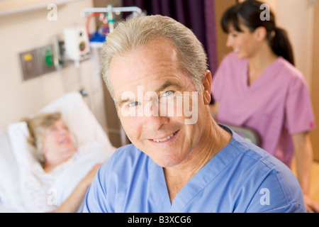Doctor Standing In Patients Room, Nurse Checking Up On Patient Stock Photo