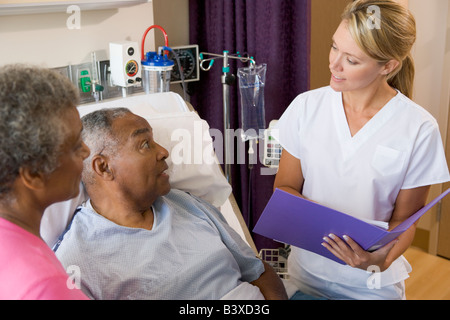 Doctor Talking To Senior Couples, Making Notes Stock Photo